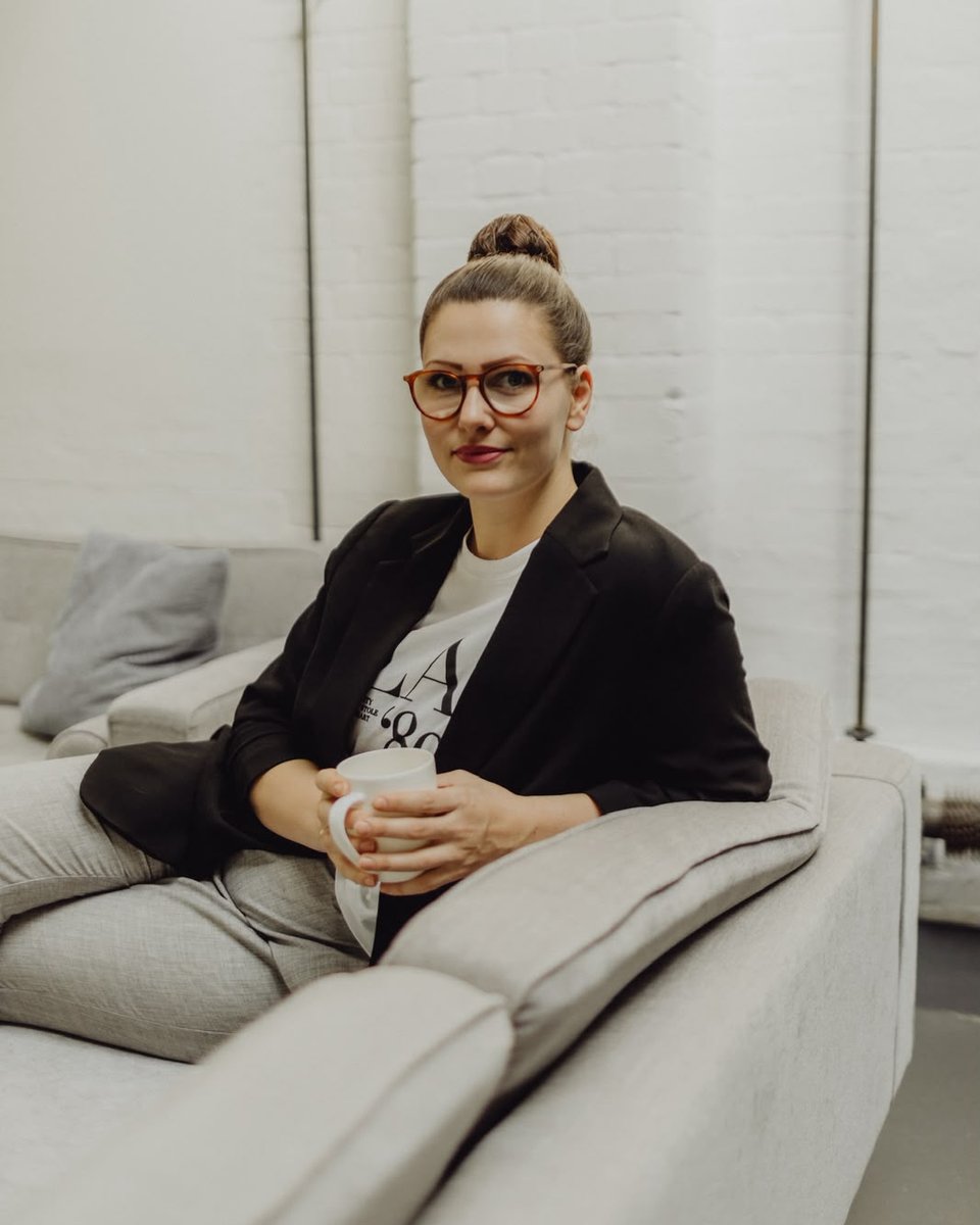 Sarah Naumann im Gespräch, mit einer Tasse auf dem Sofa